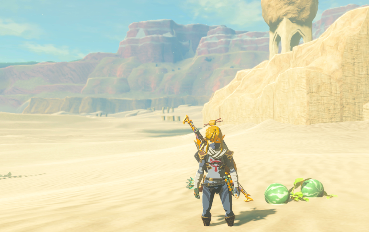 Link dressed up in the Sheikah outfit, pathetically sweats and overheats next to a pair of hydromelons in the desert sands in Tears of the Kingdom