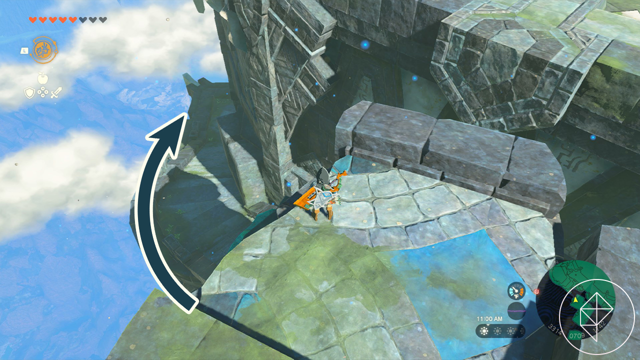 An aerial view of a stone bridge that’s separated in the middle. Link stands on the near side, and a superimposed arrow shows he should jump down continue to the left around the of the bridge to proceed.