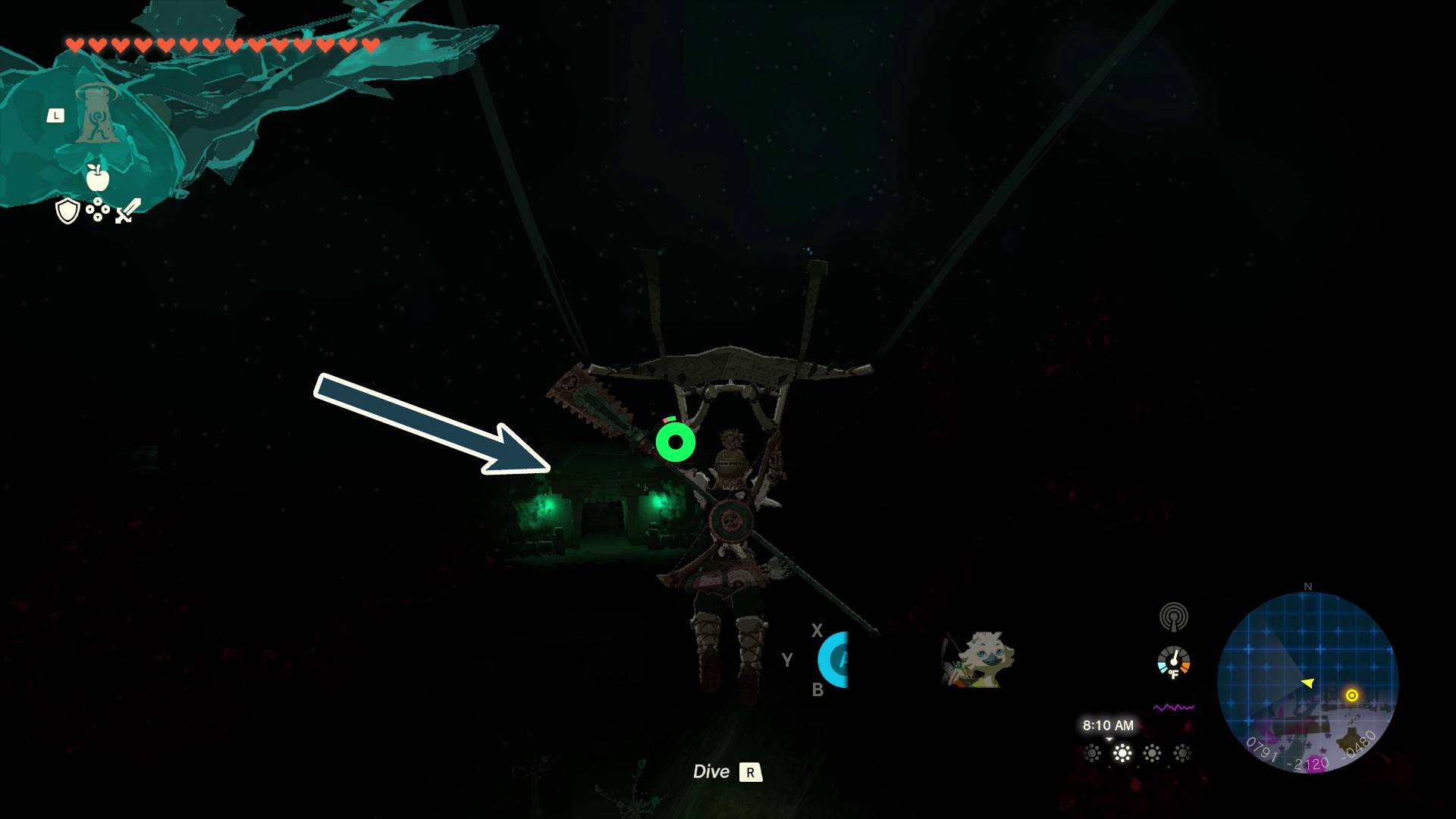 An arrow points to a cave entrance in the dark with the only light nearby from green lanterns in Tears of the Kingdom
