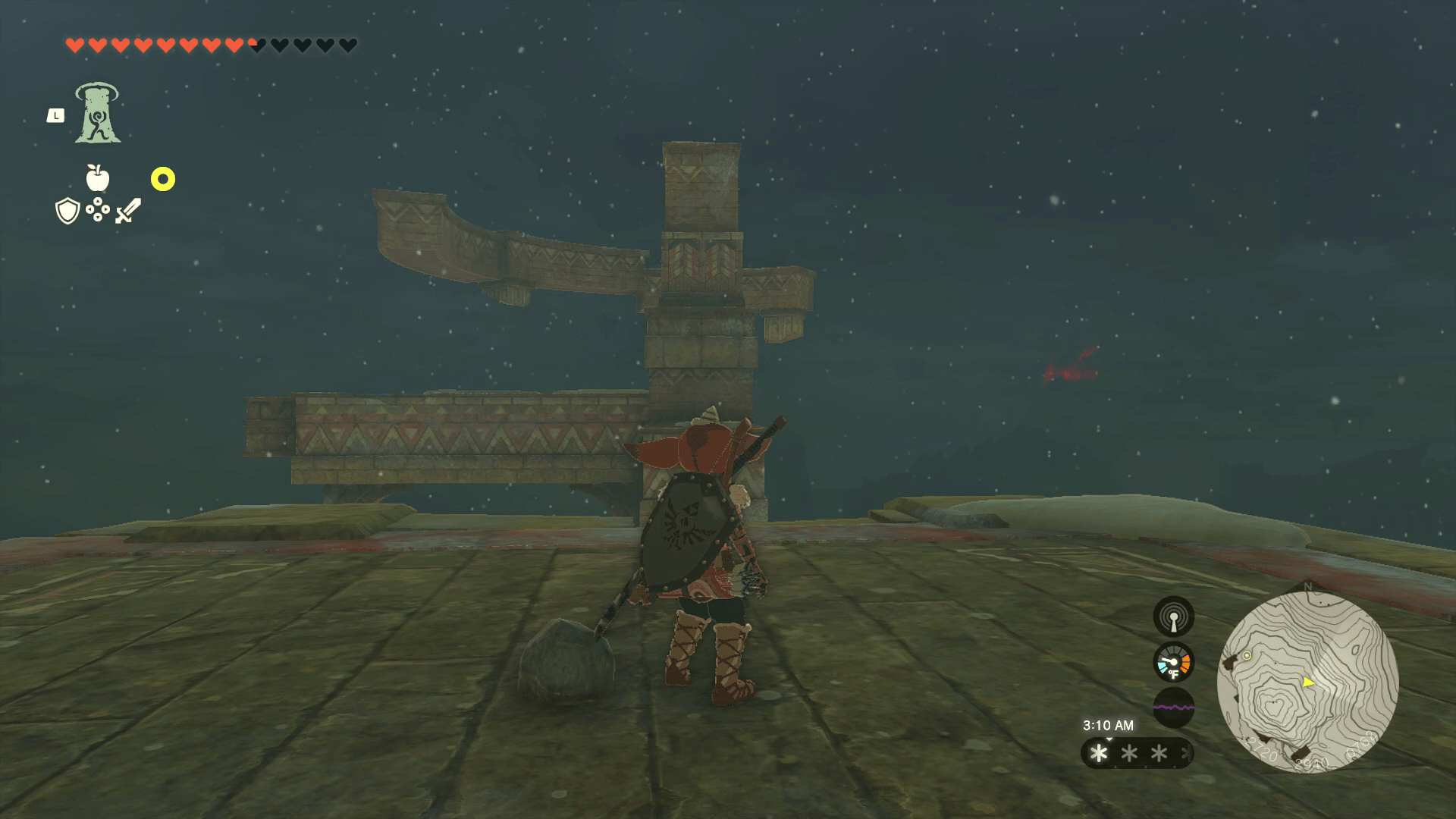 Link stands in front of a pillar made of adjoining stones, some of which jut out like long tree branches.